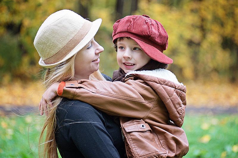 young mother holding young child outdoors in autumn
